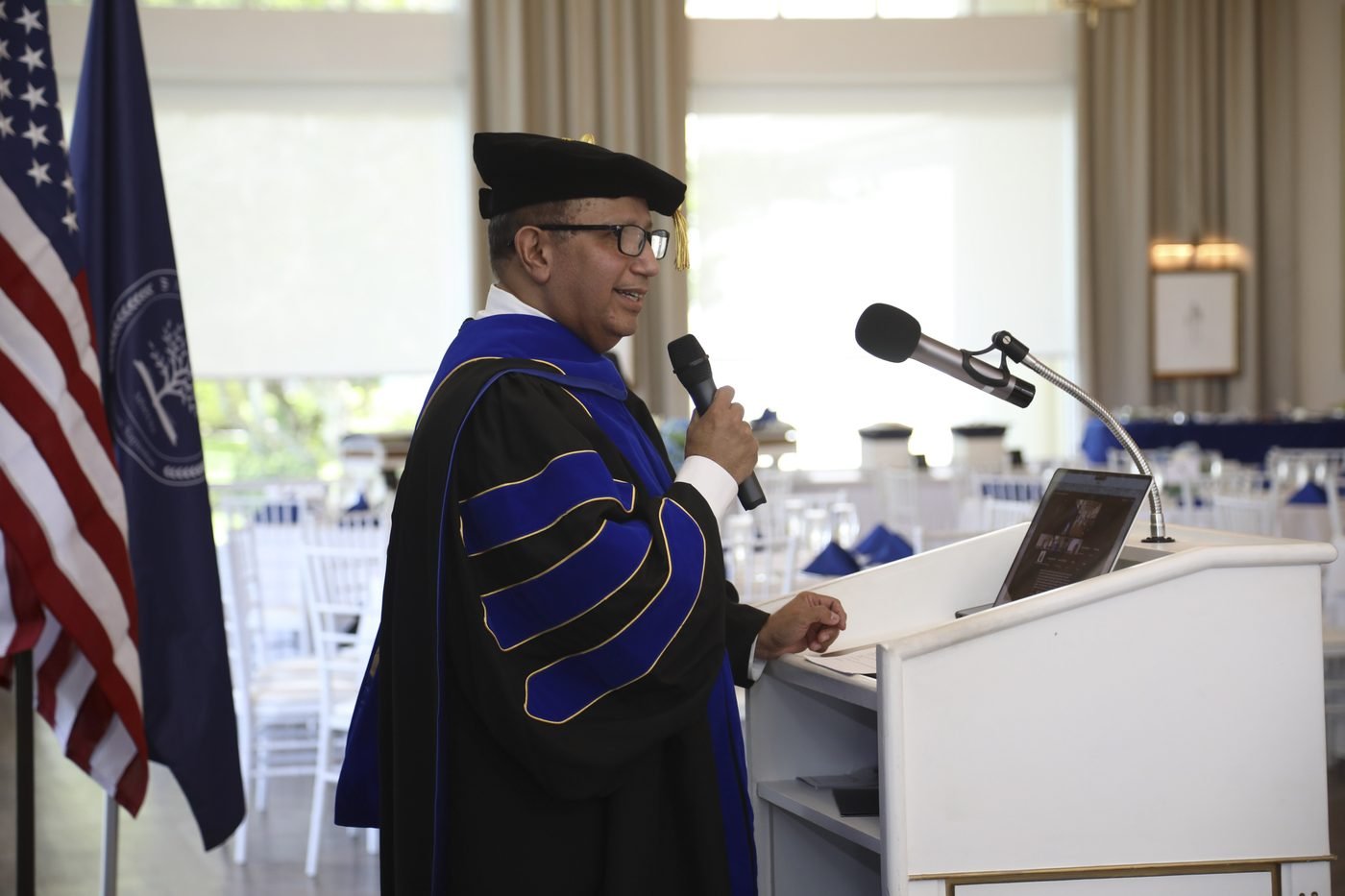 Un profesor de Aleph University pronunciando un discurso en el podio durante la ceremonia de graduación 2026.